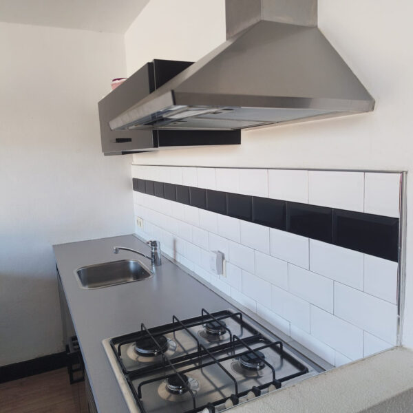 Overzicht keuken met tegelwand, grijs keukenblad en halfhoog muurtje vóór het wrappen
