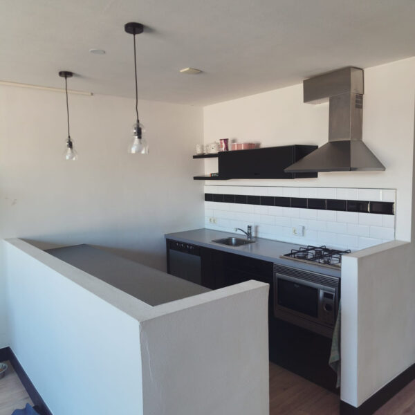 Overzicht keuken met tegelwand, grijs keukenblad en halfhoog muurtje vóór het wrappen